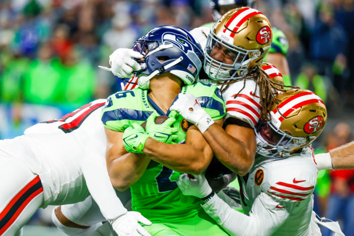 San Francisco 49ers linebacker Fred Warner (54) and linebacker Randy Gregory (5) tackle Seattle Seahawks running back Zach Charbonnet (26) on a rushing attempt.